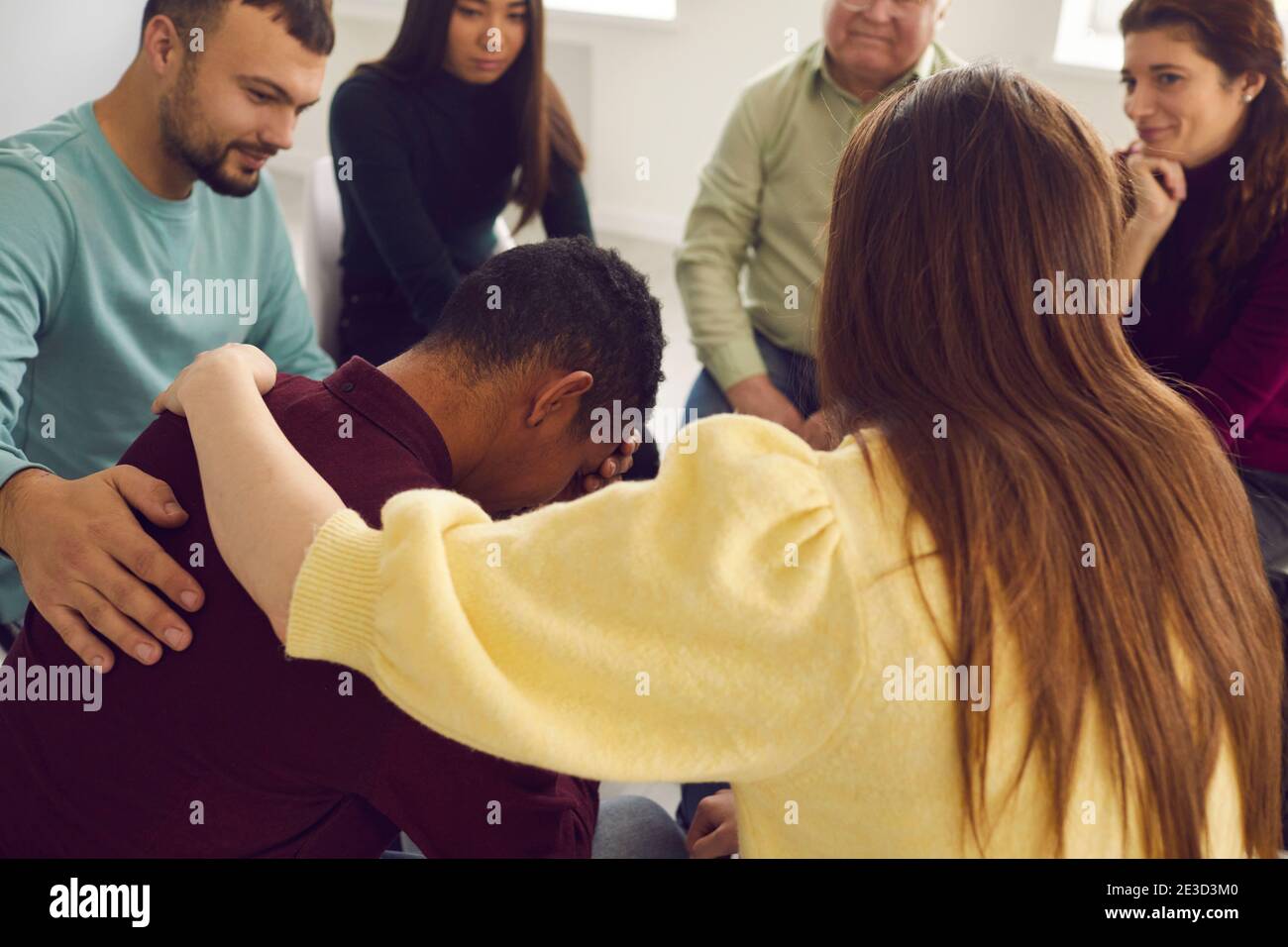 Friendly diverse people supporting an upset young man in a group therapy session Stock Photo