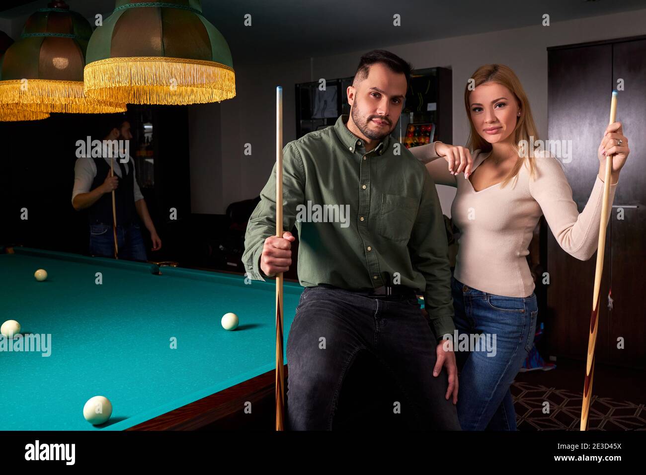 couple standing near the pool billiard table, they look at camera ...