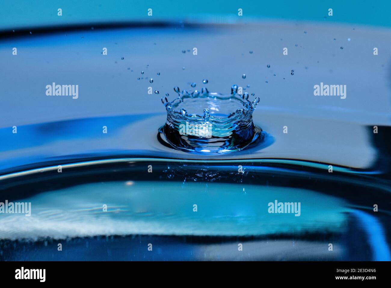 Amazing shot of a droplet bouncing and splashing on water - blue ...