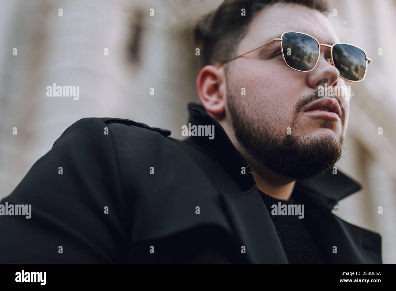 Close up of young guy wearing in black clothes while smoking and walking outdoors Stock Photo