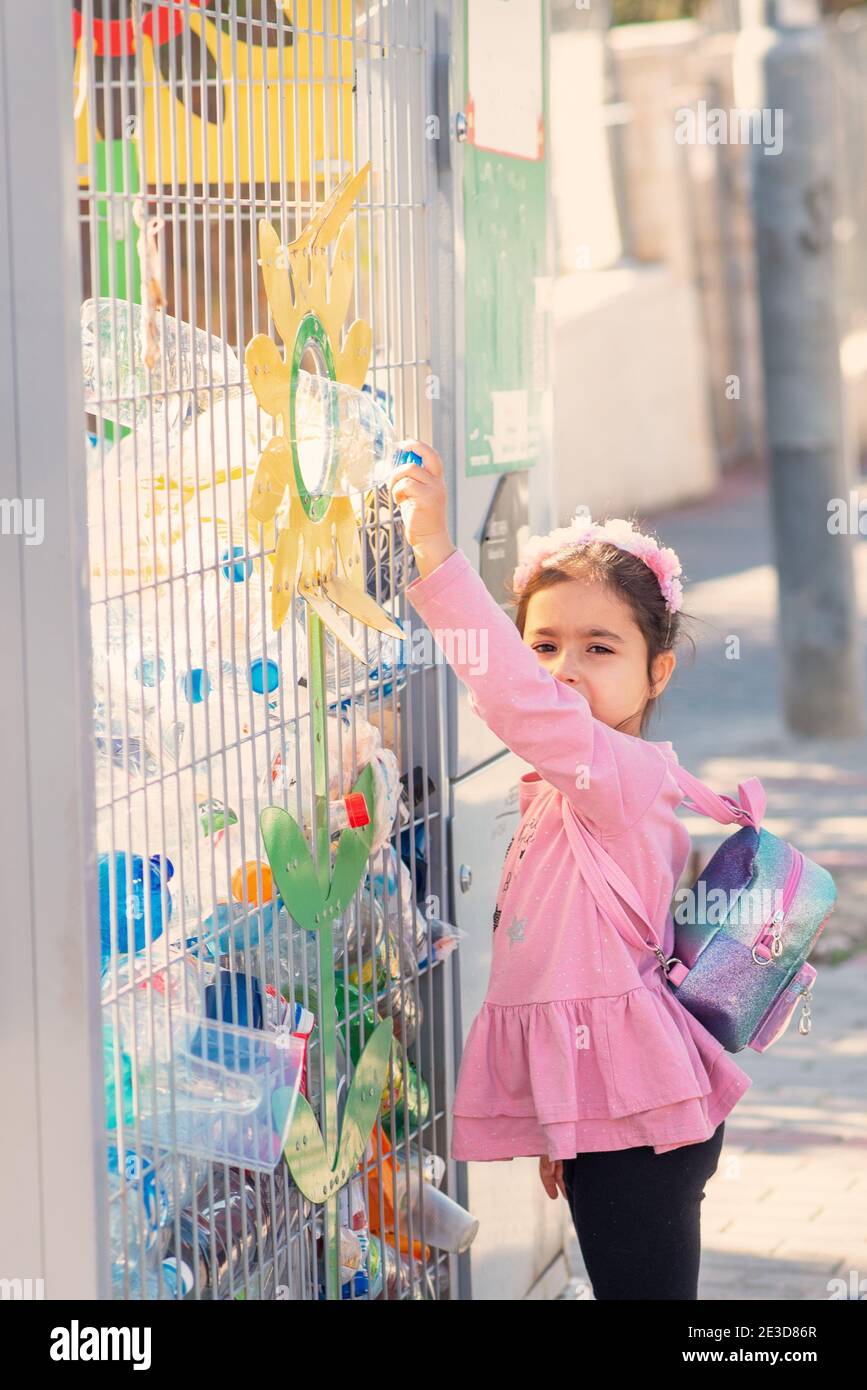 A child throwing away an empty plastic bottle to the recycling