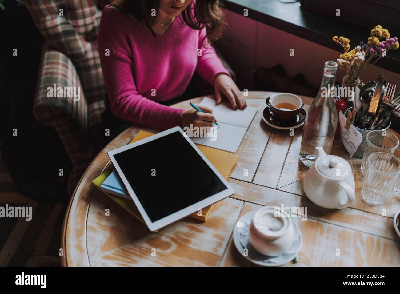 Cropped photo of attractive lady writing in notebook while sitting in coffee house Stock Photo