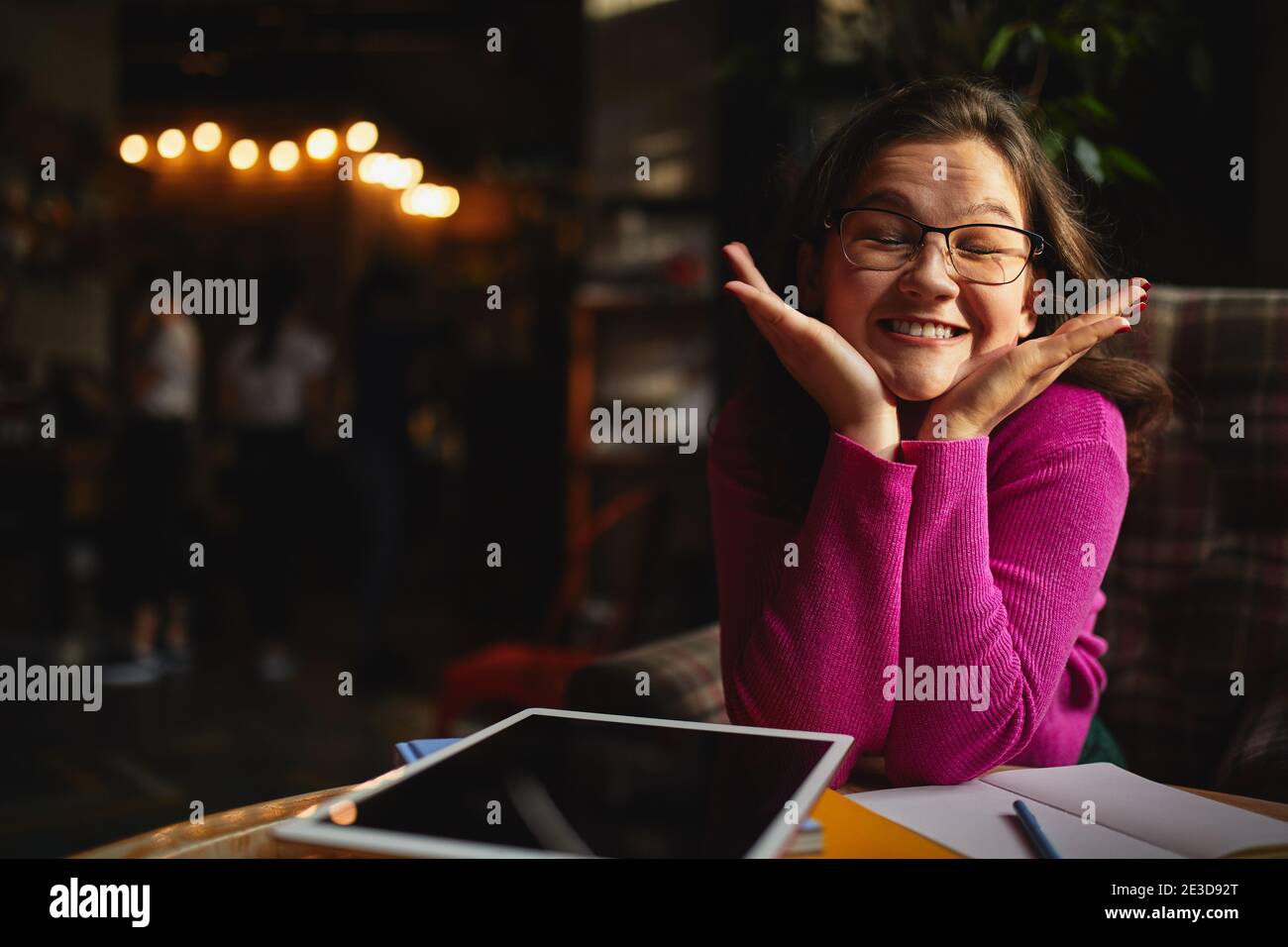 Pretty funny lady sitting at the table in coffee house and laughing while working with tablet Stock Photo