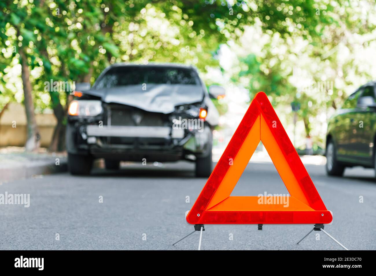 Red emergency stop triangle sign on road during a car accident. Broken gray car in road traffic accident. Car crash traffic accident on city road Stock Photo