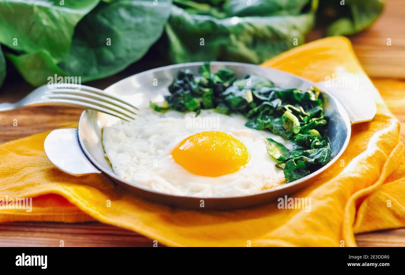 Fried egg with spinach on iron pan plate. Fried eggs healthy breakfast ...