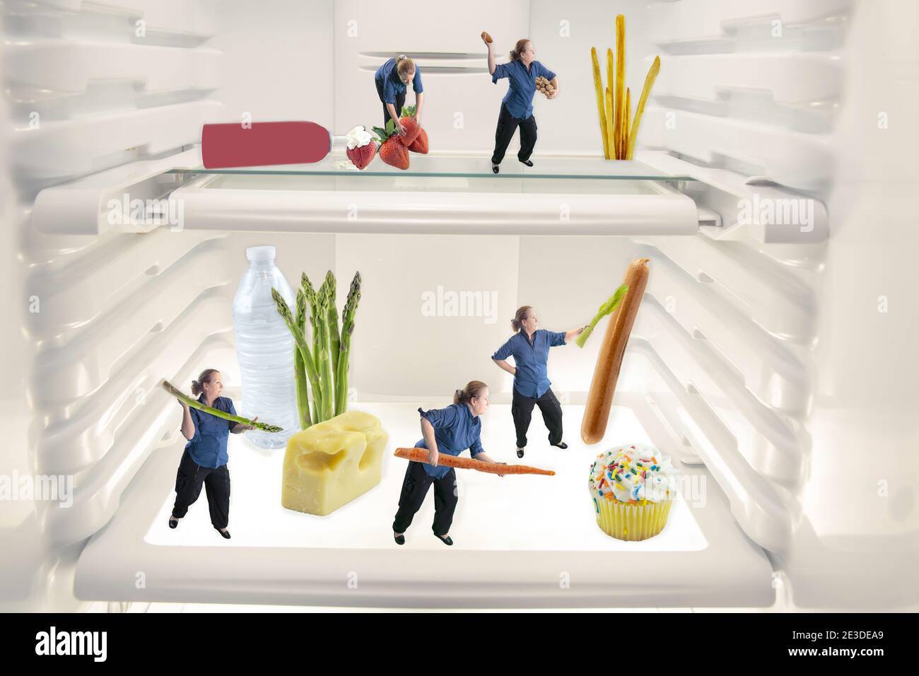 Mature woman fighting junk food with healthy food inside open refrigerator. Stock Photo
