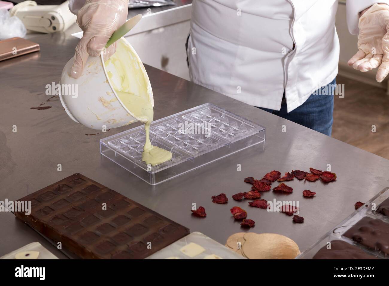 Pouring melted white chocolate into plastic molds. Closeup Stock Photo