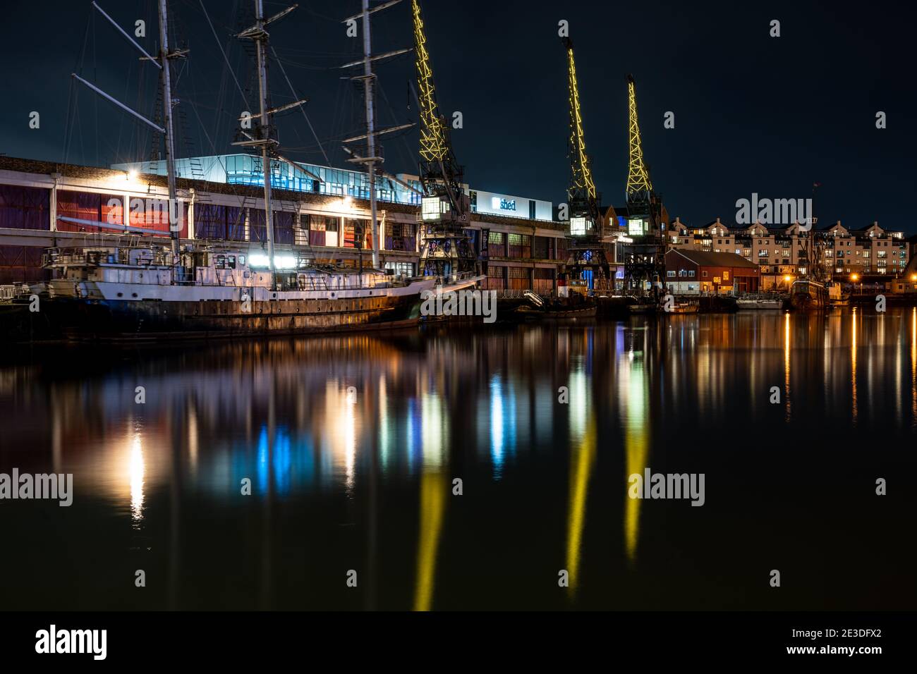Christmas lights decorate old dock cranes on the quayside of M Shed museum on Bristol's Floating Harbour. Stock Photo