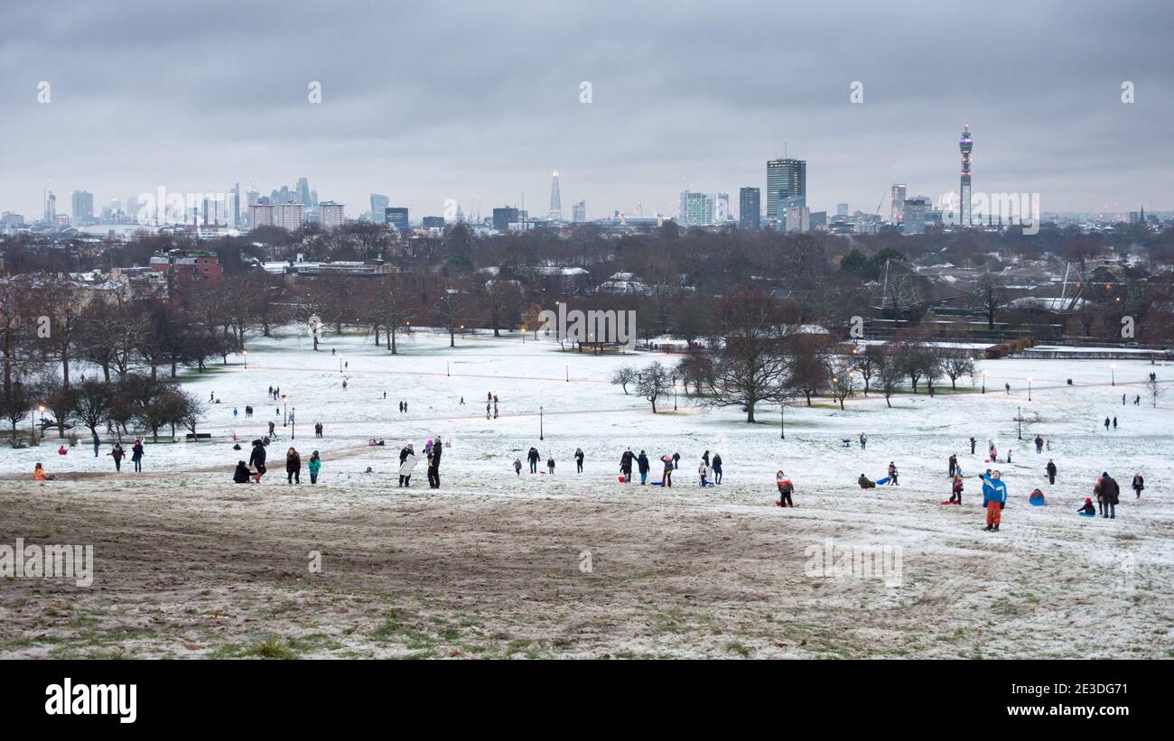 London, England, UK - December 10, 2017: Families play with sledges on Primrose Hill on a rare snow day in London, with landmarks of the City of Londo Stock Photo