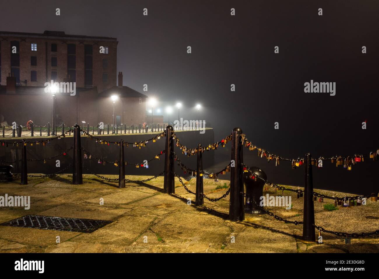 Liverpool, England, UK - November 2, 2015: Fences are covered in 'love lock' padlocks on a quayside of the River Mersey in Liverpool, with lights of B Stock Photo
