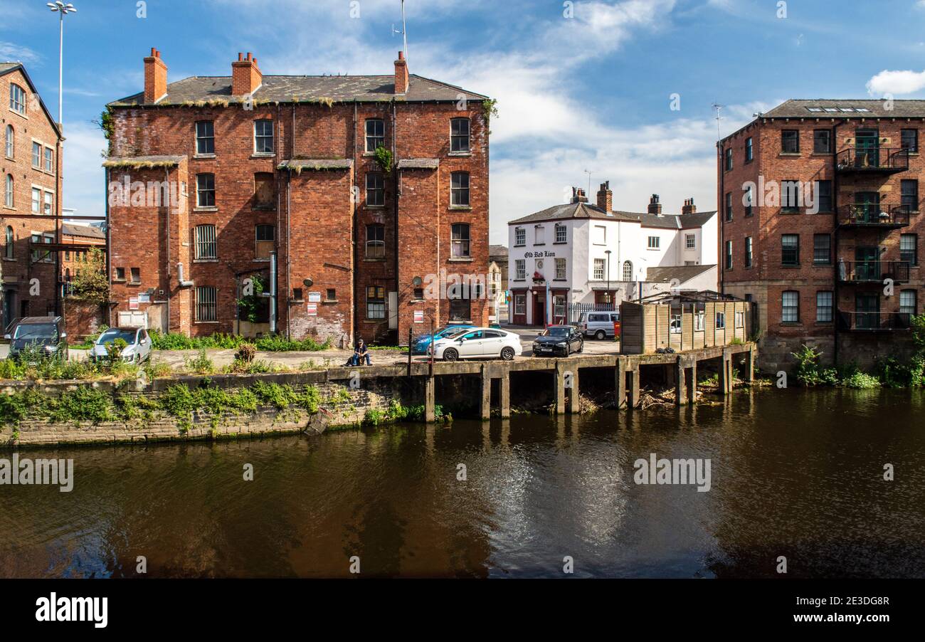 A fisherman sits on an old quayside on the River Aire in a partially regenerated post-industrial area of central Leeds. Stock Photo