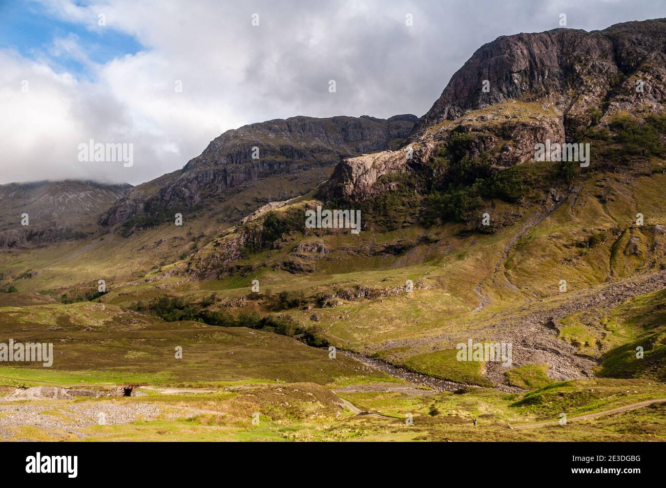 The craggy Three Sisters mountains rise above the valley and river of Glen Coe in the West Highlands of Scotland. Stock Photo