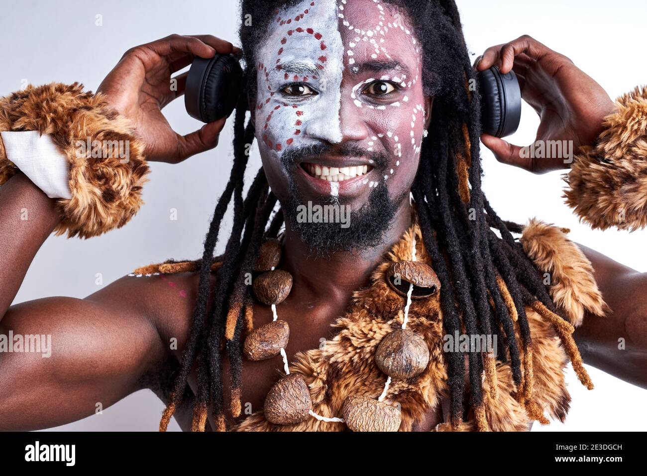 black shamanic male using headphones, holding it near ears, enjoying