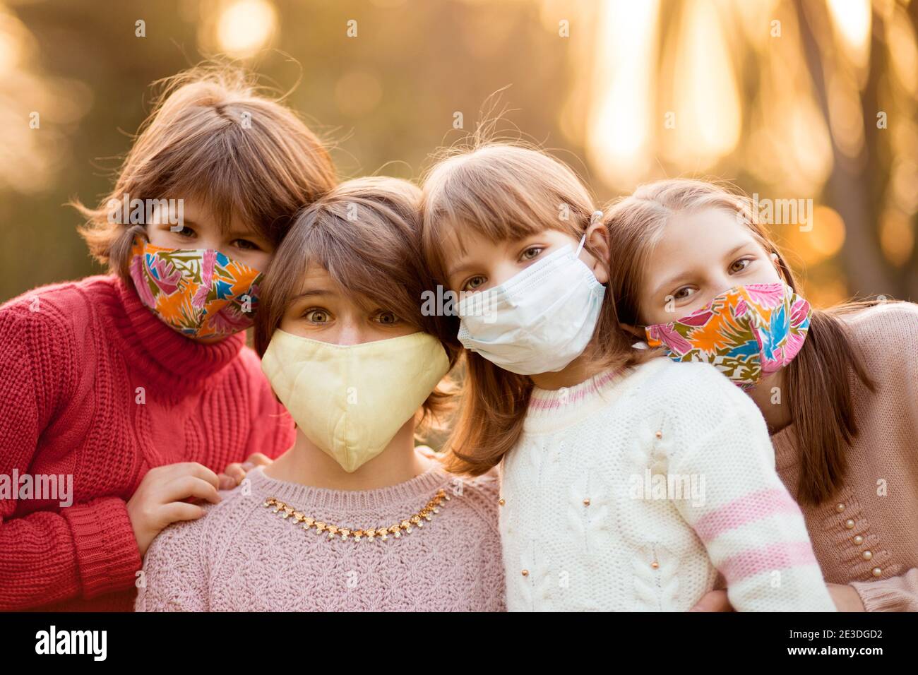 Portrait of school age children in protected face masks walk in autumn park at sunset Stock Photo