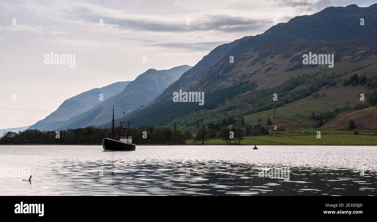 A boat is moored in Loch Lochy at Laggan Locks in the Great Glen, under the mountains of the Highlands of Scotland. Stock Photo