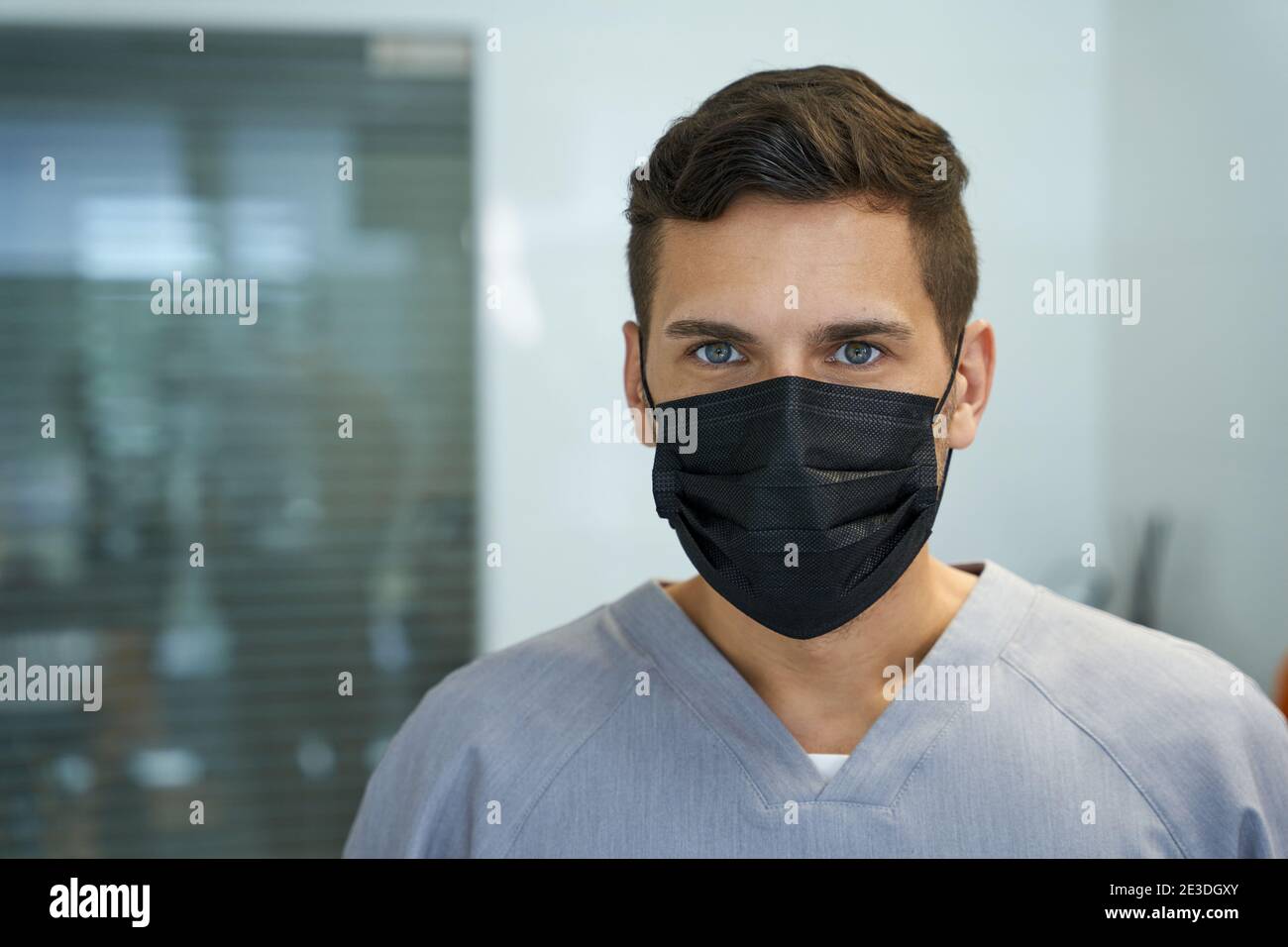 Young male doctor wearing mask and posing for camera Stock Photo