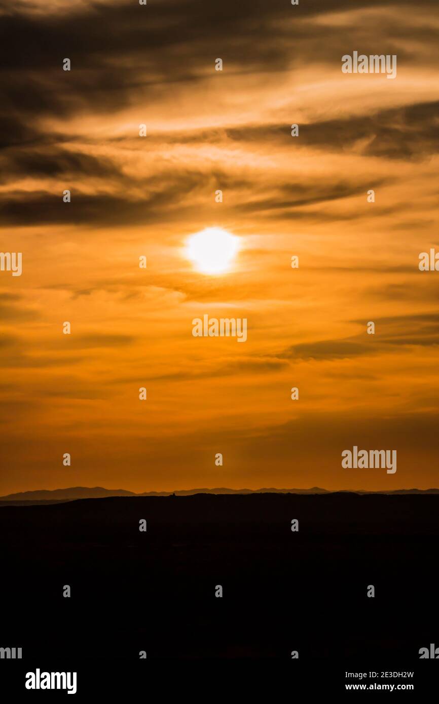 A landscape of the golden sky, the silhouetted earth and the setting sun Stock Photo