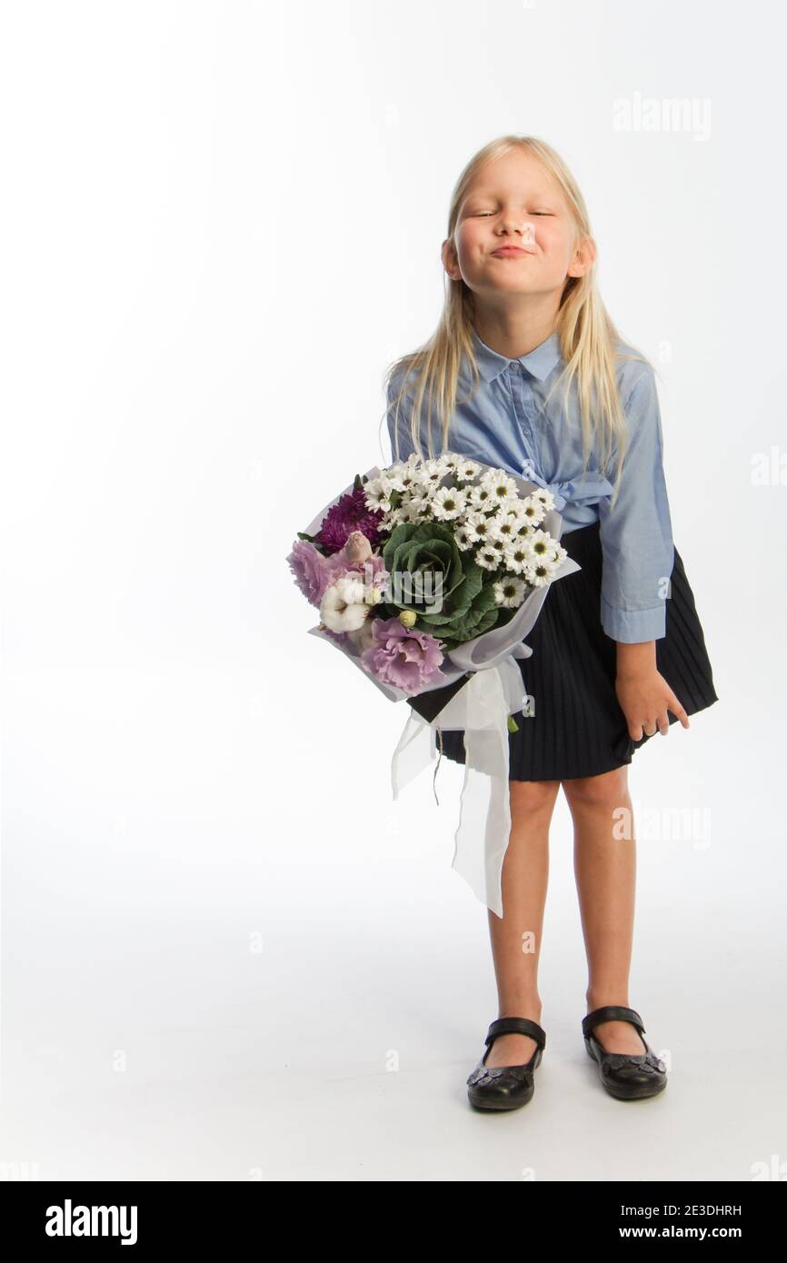 Studio portrait of cute blonde girl in school uniform with beautiful gift bouquet, white backdrop, selective focus Stock Photo