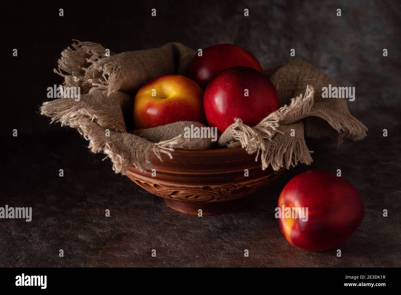 Ripe and juicy nectarines in a bowl on a table on a dark background.  Stock Photo