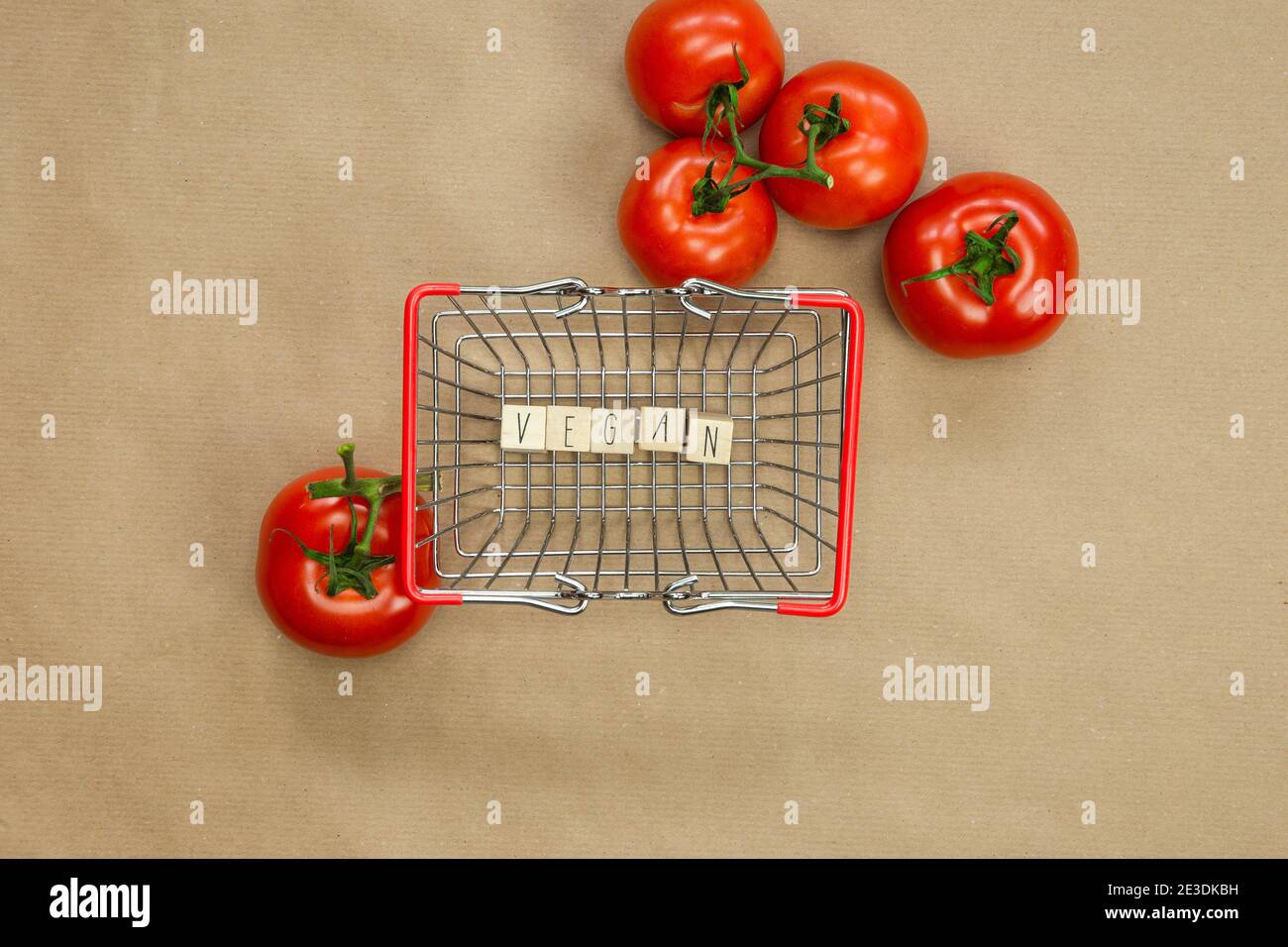 Vegan written on wooden cubes surrounded with vegetables in shoppin