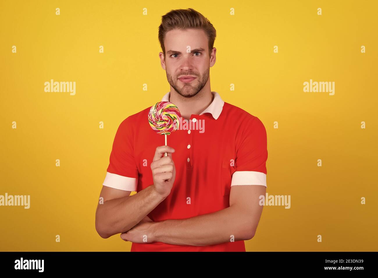 Taste the rainbow. Man candy yellow background. Handsome guy hold candy on stick. Candy shop. Lollipop or sucker. Sugary treat. Candy factory and confectionary. Stock Photo