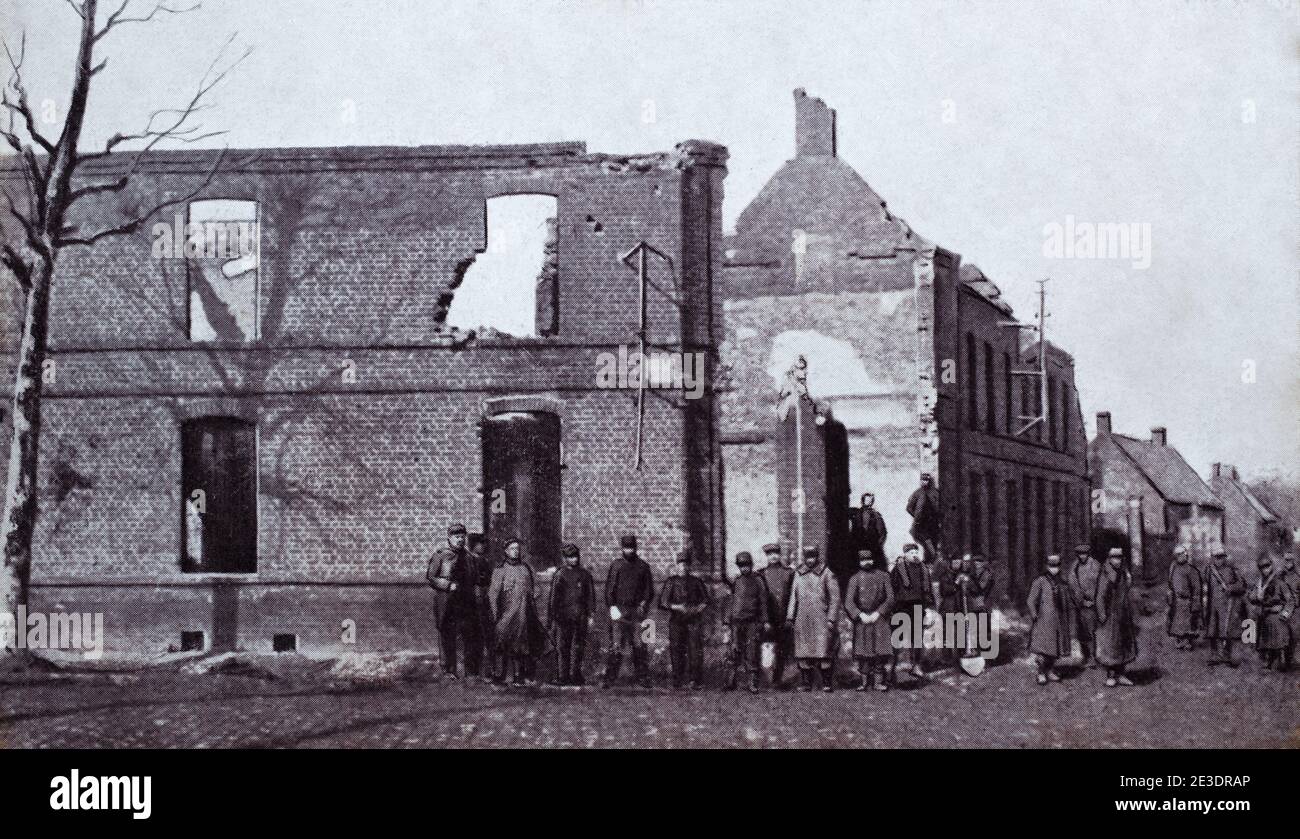 A historical view of a group of French soldiers in front of damaged buildings in Cambrin, Pas-de-Calais. France. Taken from a postcard c. 1914-1915. Stock Photo