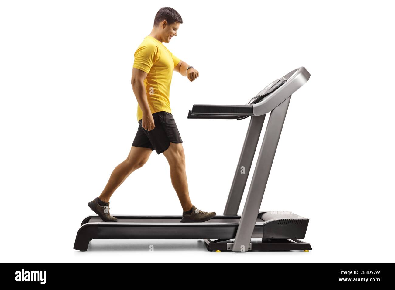 Man in sportswear walking on a treadmill and looking at his smartwatch isolated on white background Stock Photo