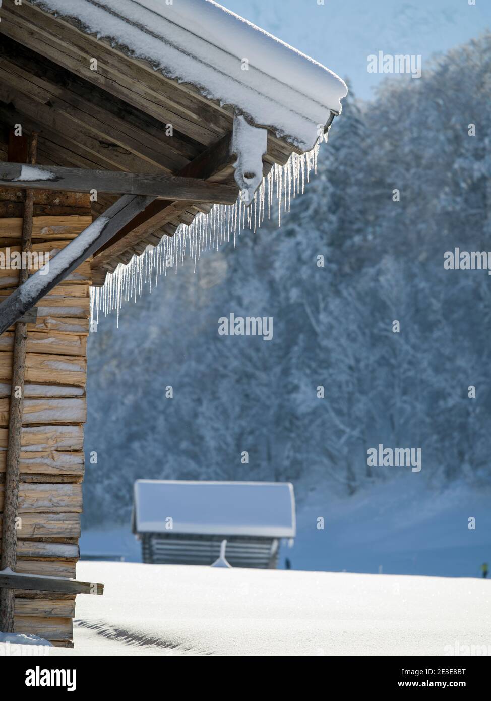 Wooden huts covered in snow and perfectly lined up icicles Stock Photo