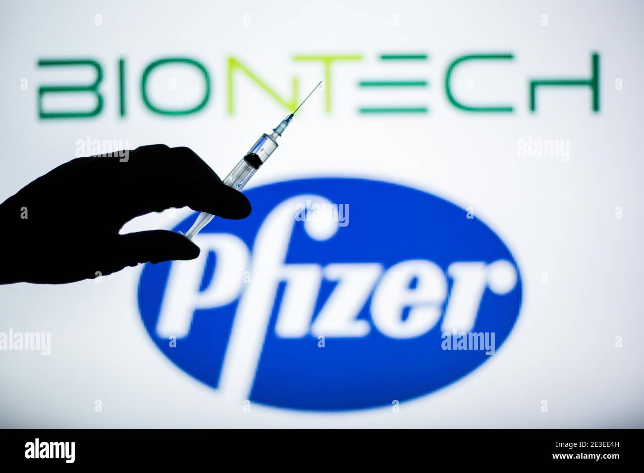 Spain. 18th Jan, 2021. In this illustration, a hand of a person seen holding a syringe in front of the Pfizer and BioNTech logo.Spain begins to administer the second dose of the Pfizer and BioNTech drug vaccine and the first dose (35,700 doses) of Moderna's drug has been incorporated, which also requires two injections per person. Credit: Thiago Prudencio/SOPA Images/ZUMA Wire/Alamy Live News Stock Photo