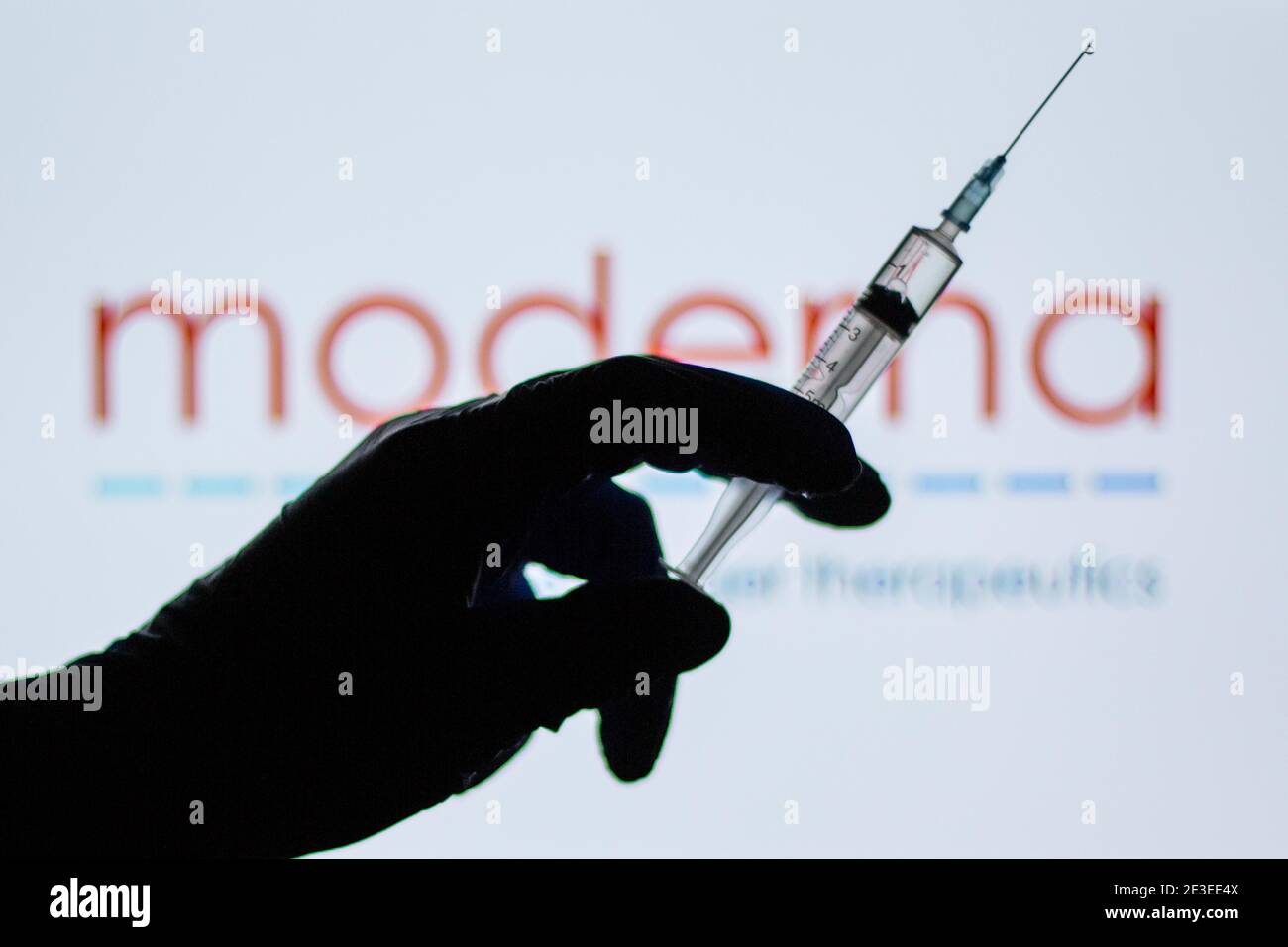 Spain. 18th Jan, 2021. In this illustration, a hand of a person seen holding a syringe in front of the Moderna logo.Spain begins to administer the second dose of the Pfizer and BioNTech drug vaccine and the first dose (35,700 doses) of Moderna's drug has been incorporated, which also requires two injections per person. Credit: Thiago Prudencio/SOPA Images/ZUMA Wire/Alamy Live News Stock Photo