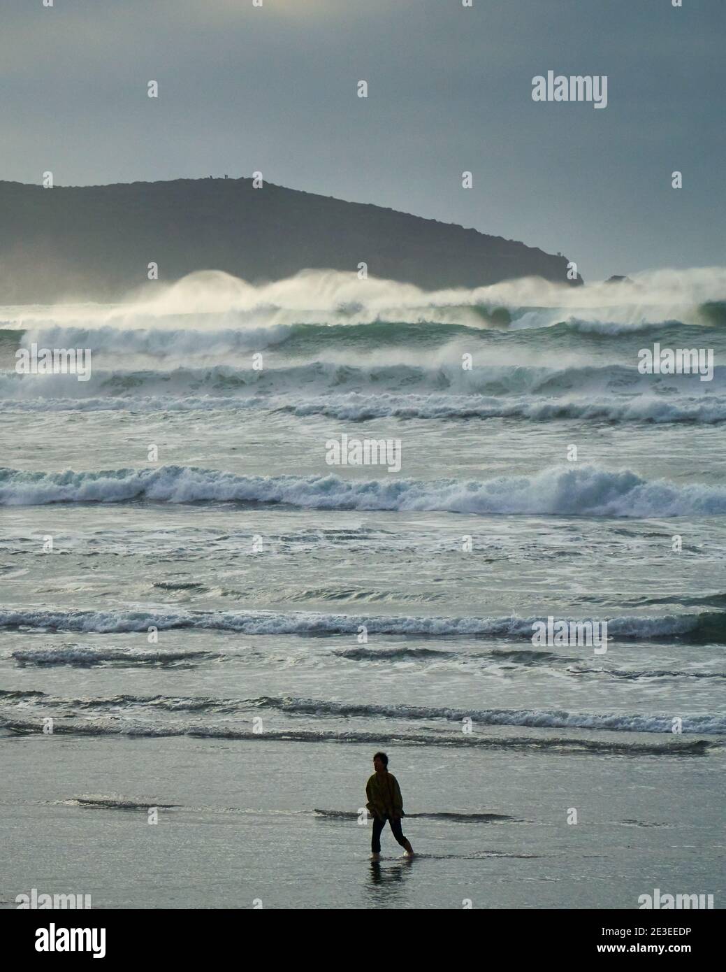 A person walks on beach during rough surf and high waves. Dillon Beach