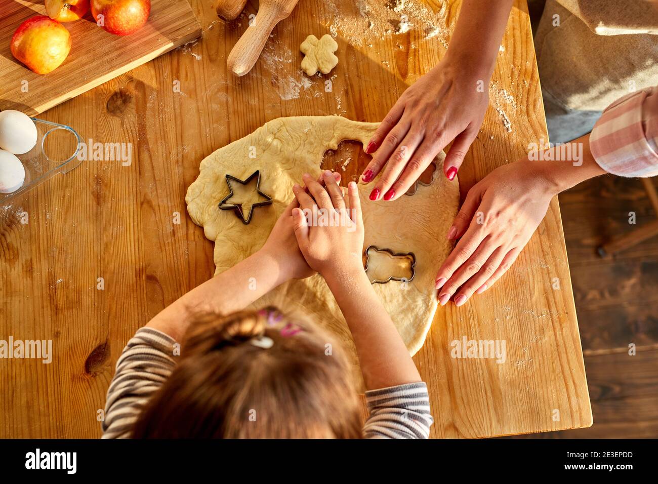 mother teaching daughter how to make cookies from dough using cookie