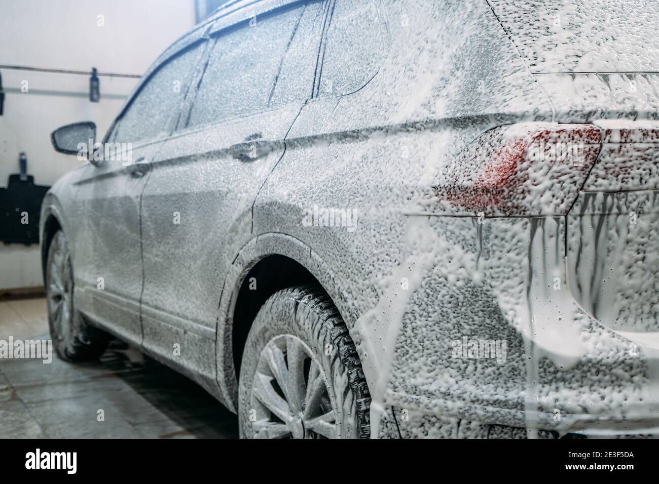 Application of first phase on dirty auto. Foam covering car at car wash. Car Detailing Stock