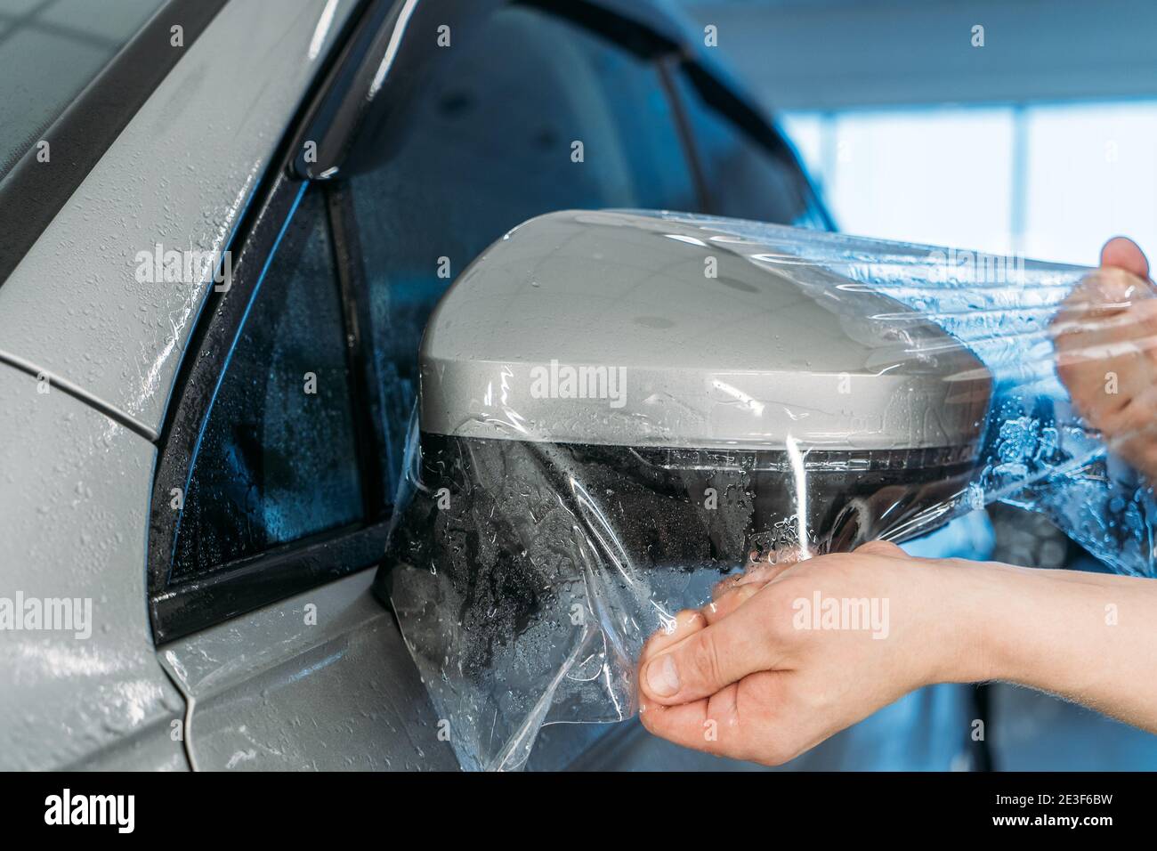 Männliche Wrapper hält Sonnenschutzfolie, Auto Färbung Service. Arbeiter,  der Vinylfarbe auf das Fahrzeugfenster in der Garage aufgibt  Stockfotografie - Alamy
