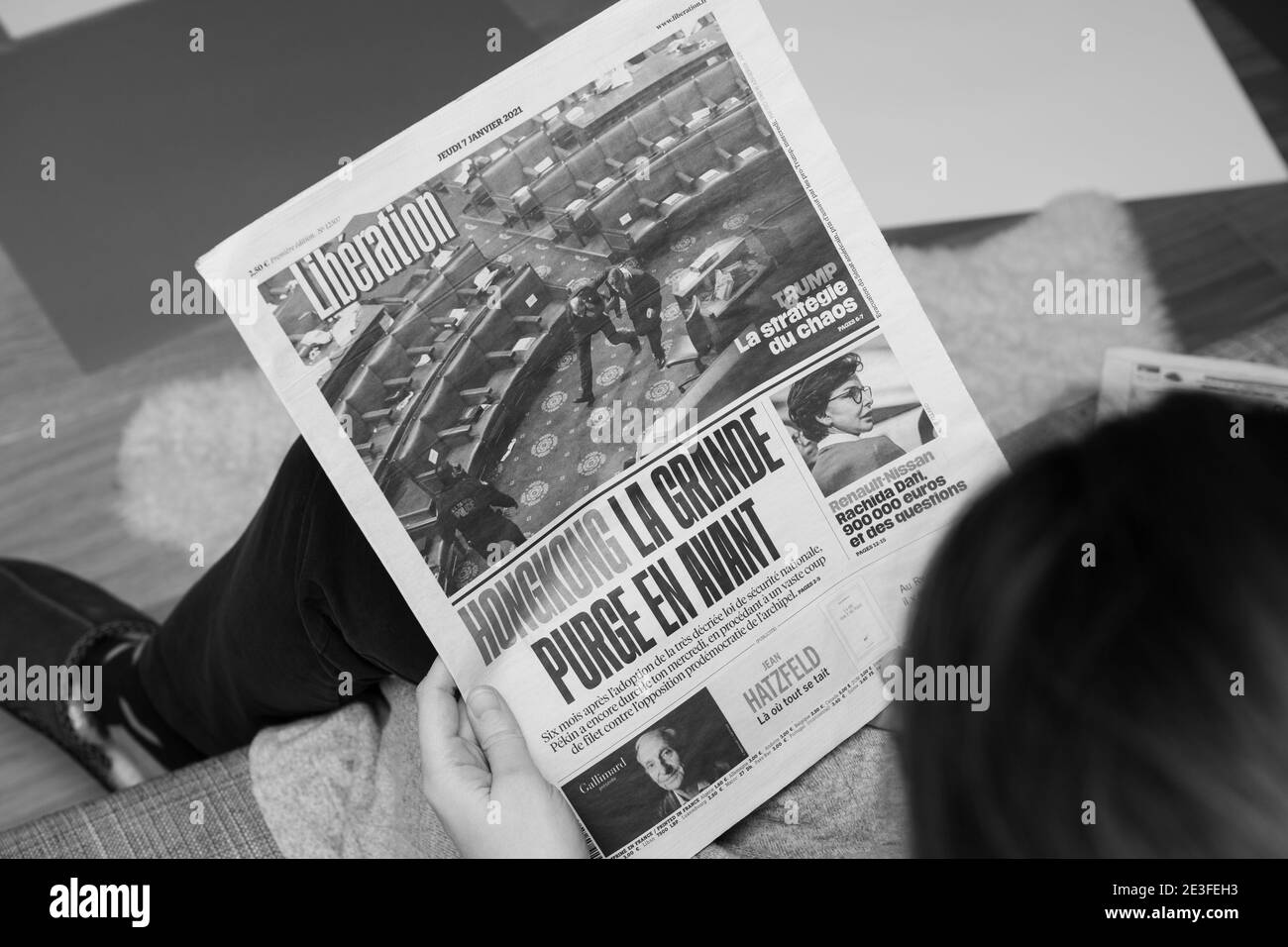 Paris, France - Jan 7, 2020: black and white image woman reading on couch French newspaper Liberation in front page show storming of the U.S. Capitol by supporters of U.S. President Donald Trump Stock Photo