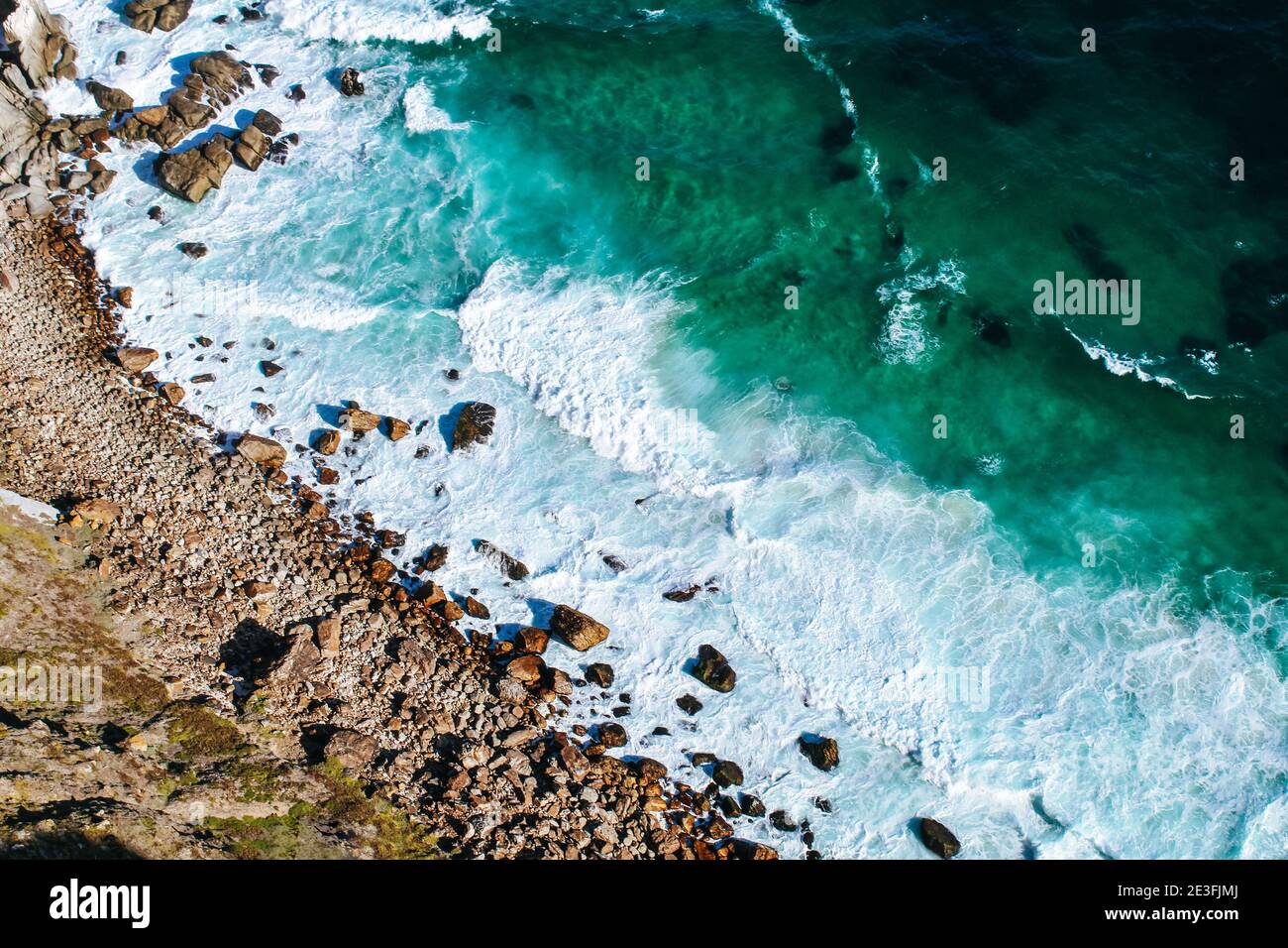 Background texture of a rocky shore and blue and turquoise water and waves of the Atlantic Ocean at the Cape of Good Hope in South Africa Stock Photo