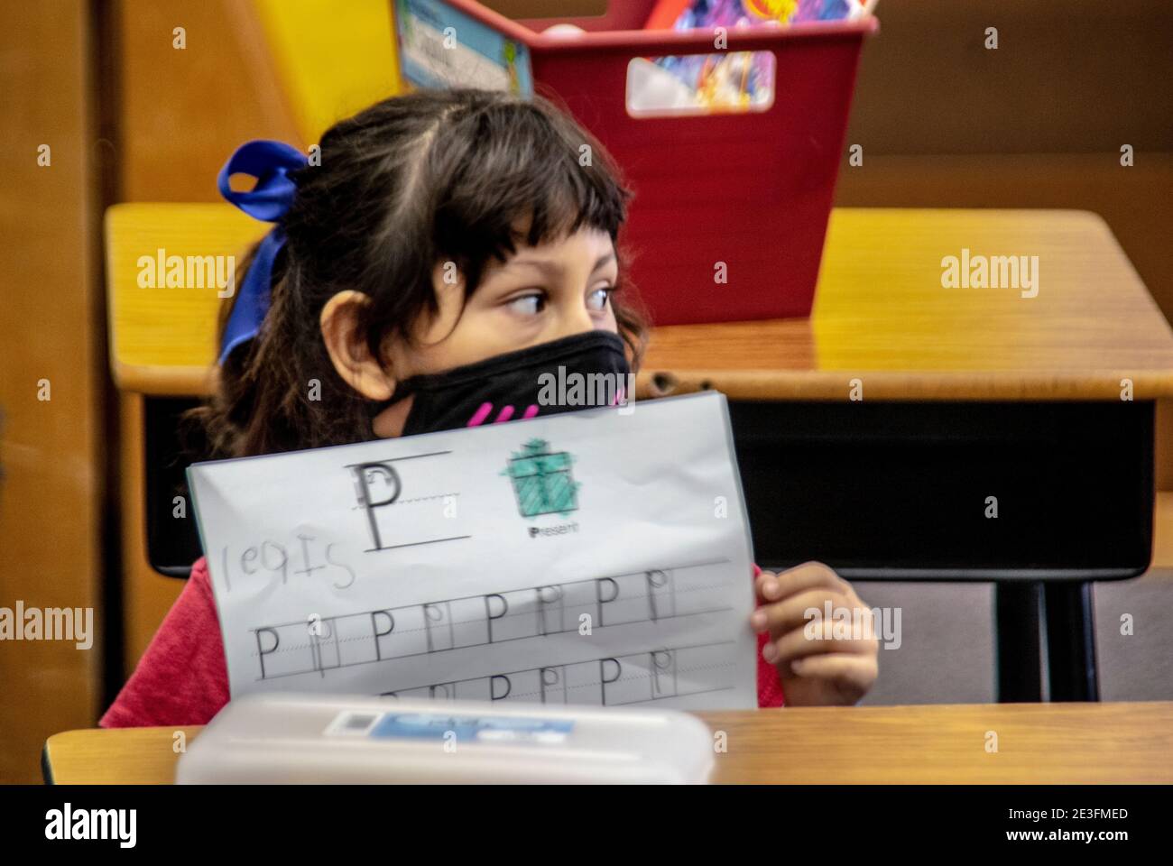 A Hispanic first grader at a California elementary school displays her paper to show she understands the letter P. Note mask due to coronavirus pandem Stock Photo