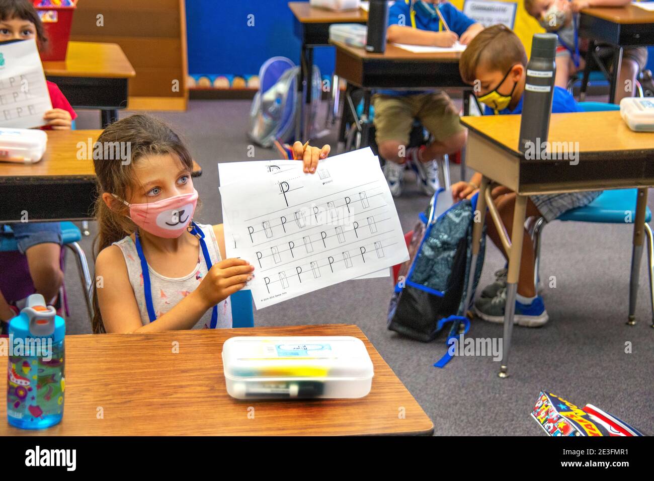A first grader at a California elementary school displays her paper to show she understands the letter P. NoteHispanic mask due to coronavirus pandemi Stock Photo