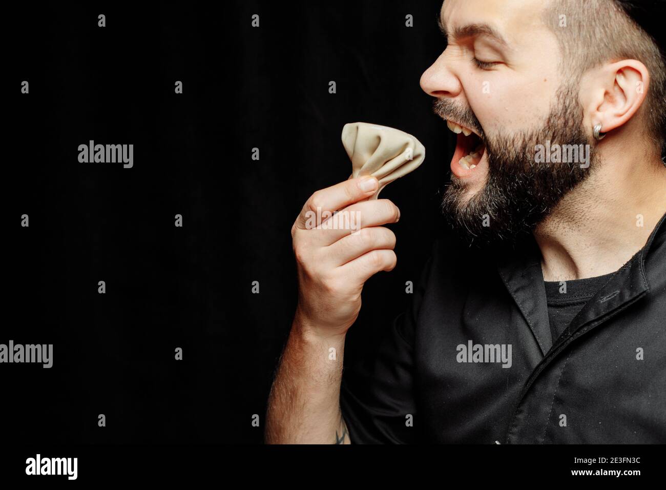 The bearded man is emotionally eating khinkali. The national Georgian dish khinkali. Concept of advertising photo of khinkali Stock Photo