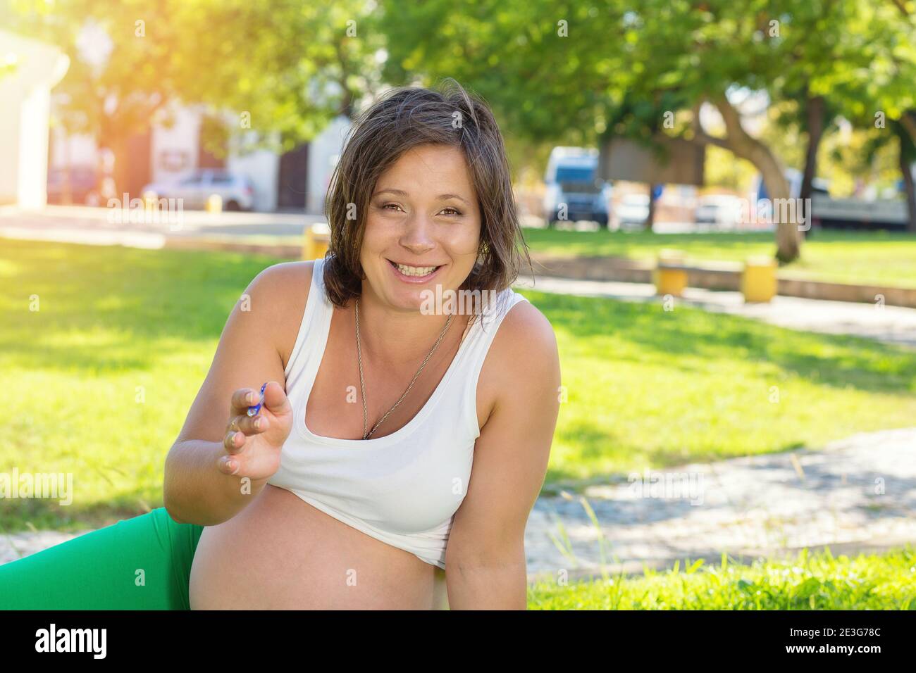 Smiling pregnant woman talking with distant client looking at camera, record shoot video training online training webinar video blog, sitting outdoors Stock Photo