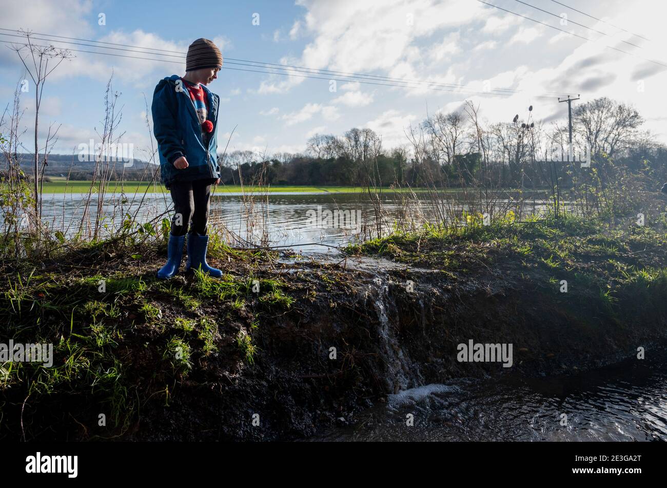 9 year old boy and his dog in and by a flooded field near Burham in Kent, UK after heavy rain January 2021 Stock Photo