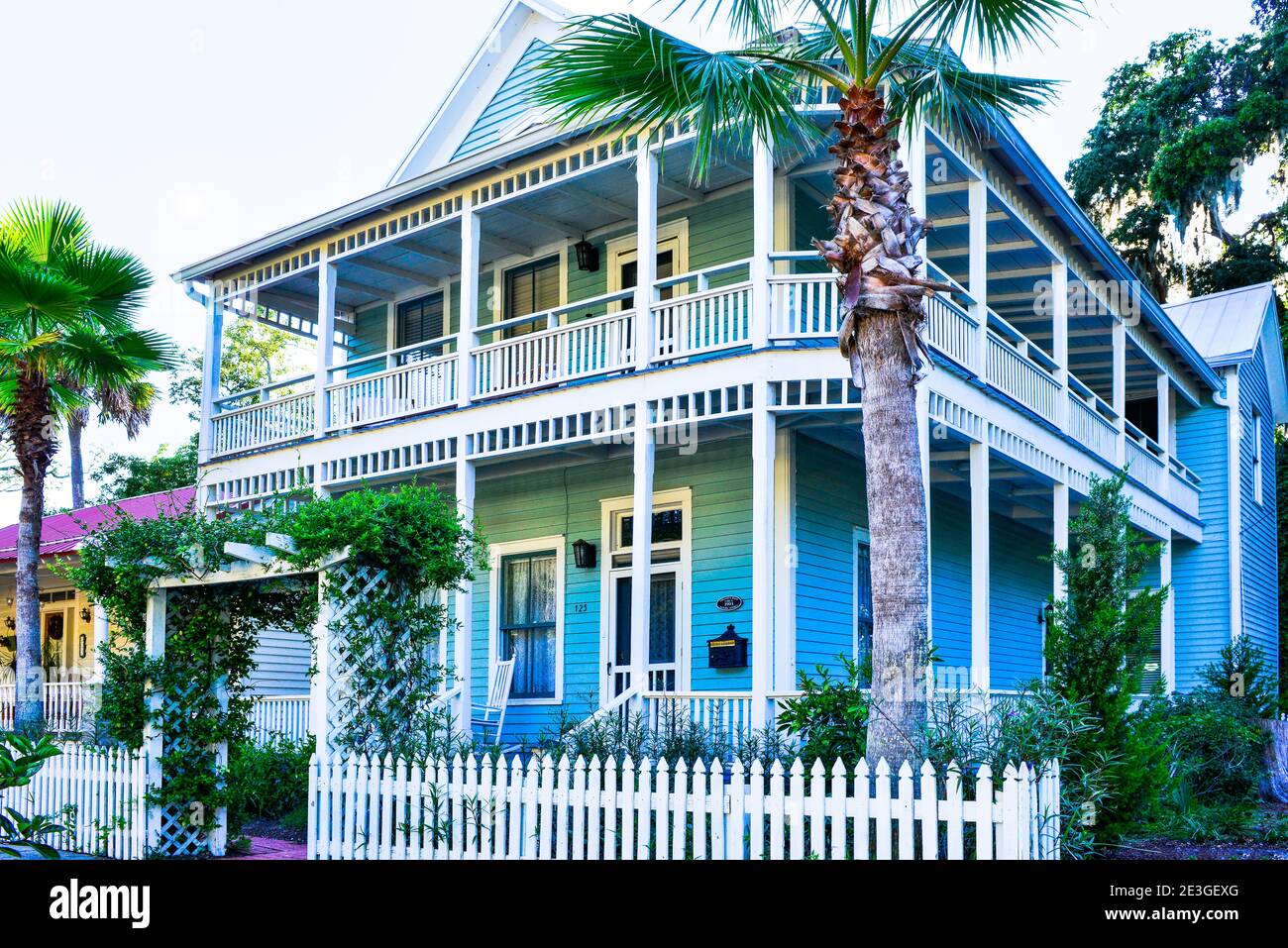 A two storied blue wooden home with balcony and front porch and rocking chairs on Amelia Island, in historical downtown Fernandina Beach, FL Stock Photo