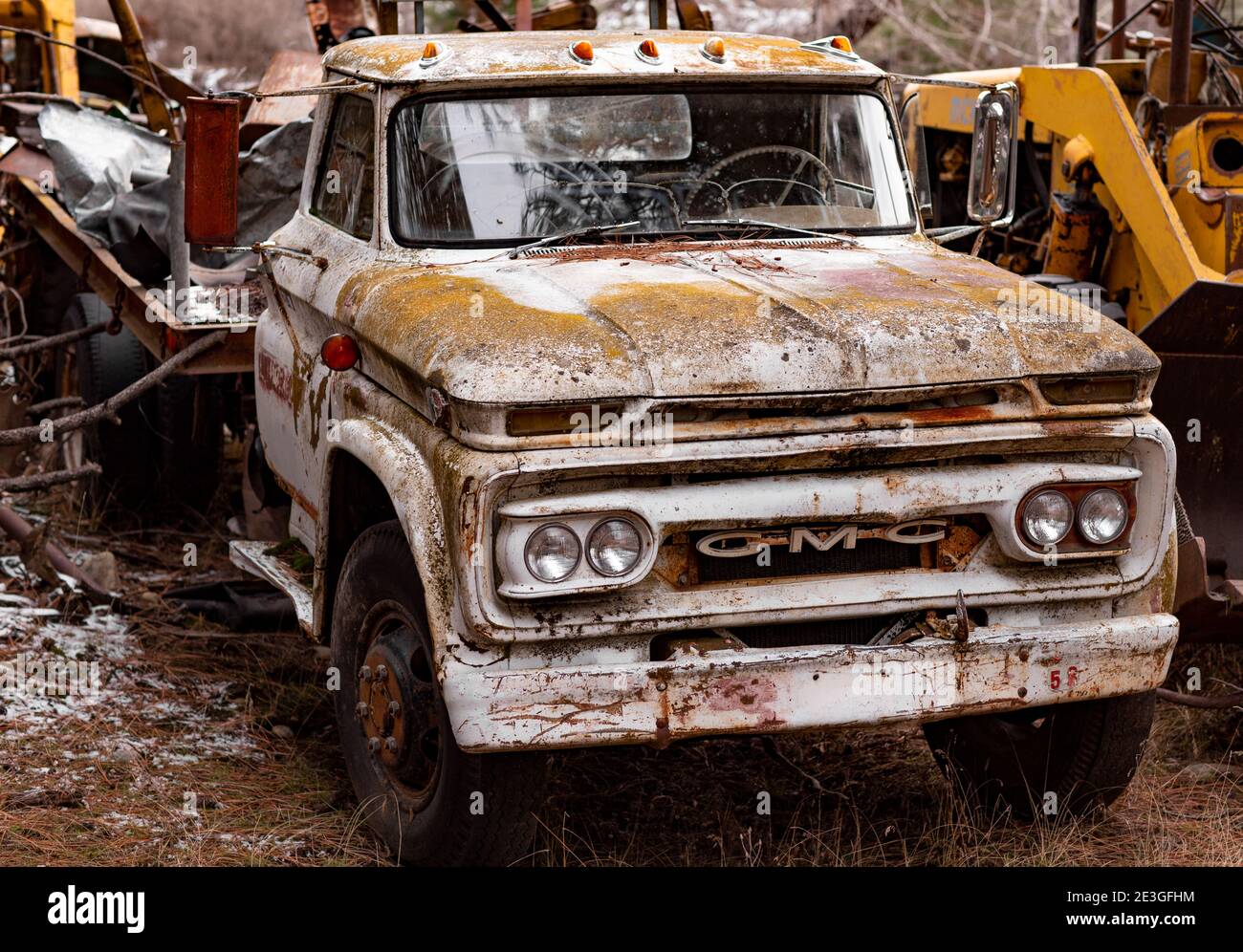 A rusty, white 1965 GMC 4000 2 1/2 ton stakebody work truck, at a