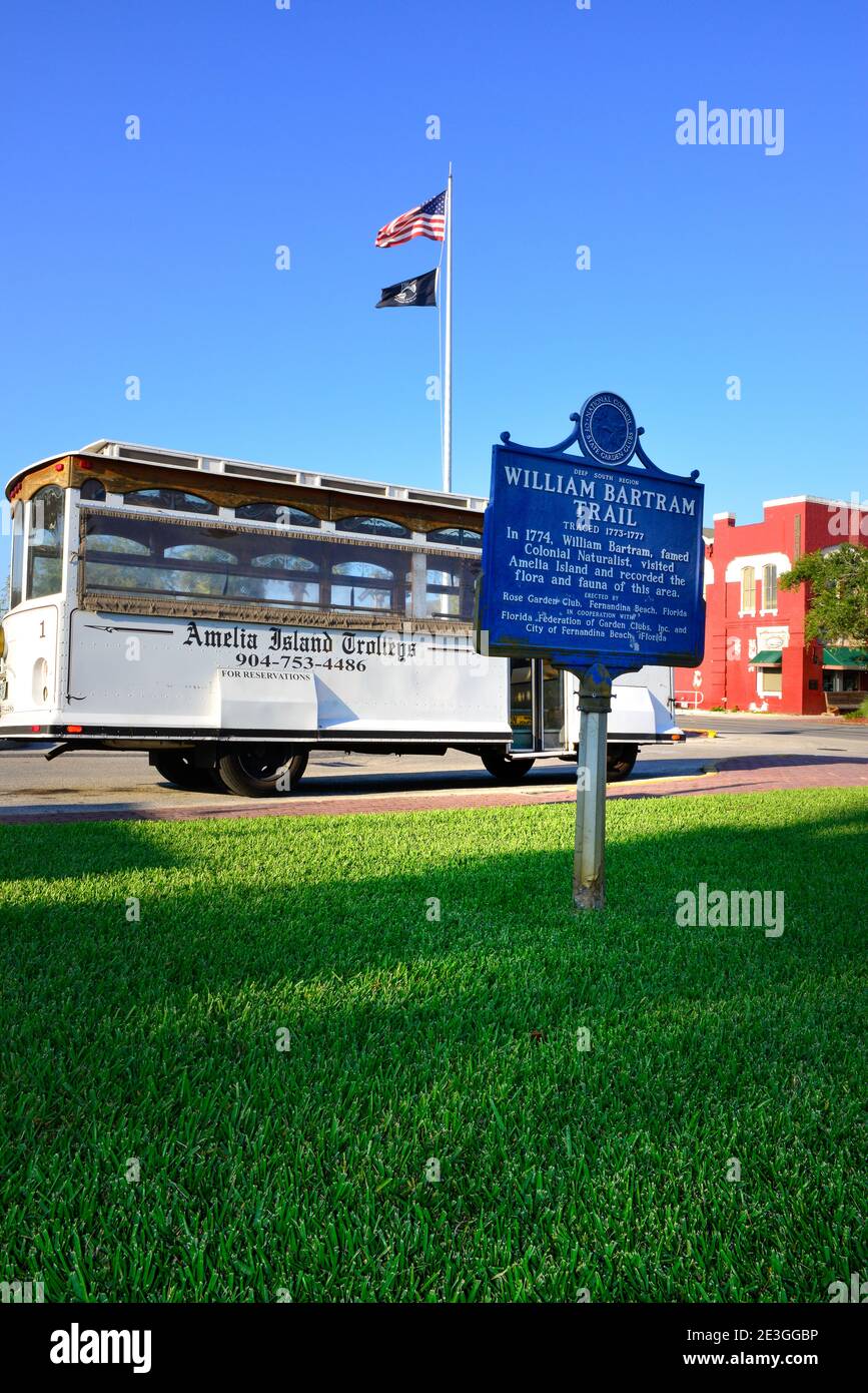 A Vintage tour bus of Amelia Island Trolleys, in historic district of Fernandina Beach, with historical sign for the Naturalist, William Bartram, FL Stock Photo