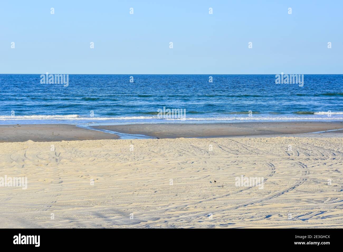 In a stark, empty beach scene, a lone yellow beach chair faces the Atlantic Ocean on Fernandina Beach, on Amelia Island, FL Stock Photo