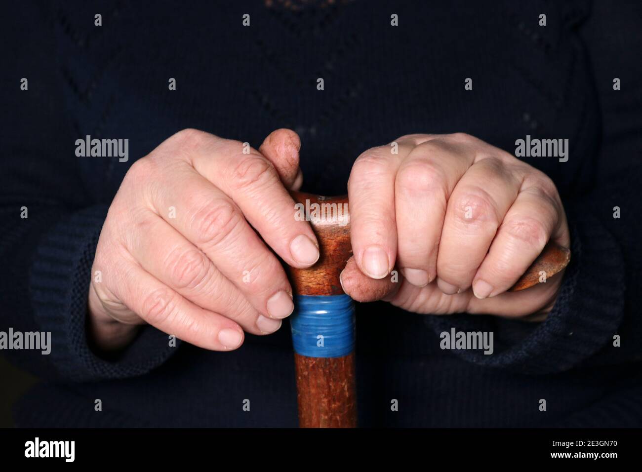 Senior woman's hands on old walking stick with t shaped handles. The concept of old age, loneliness, solicitude and caring for the elderly. Stock Photo
