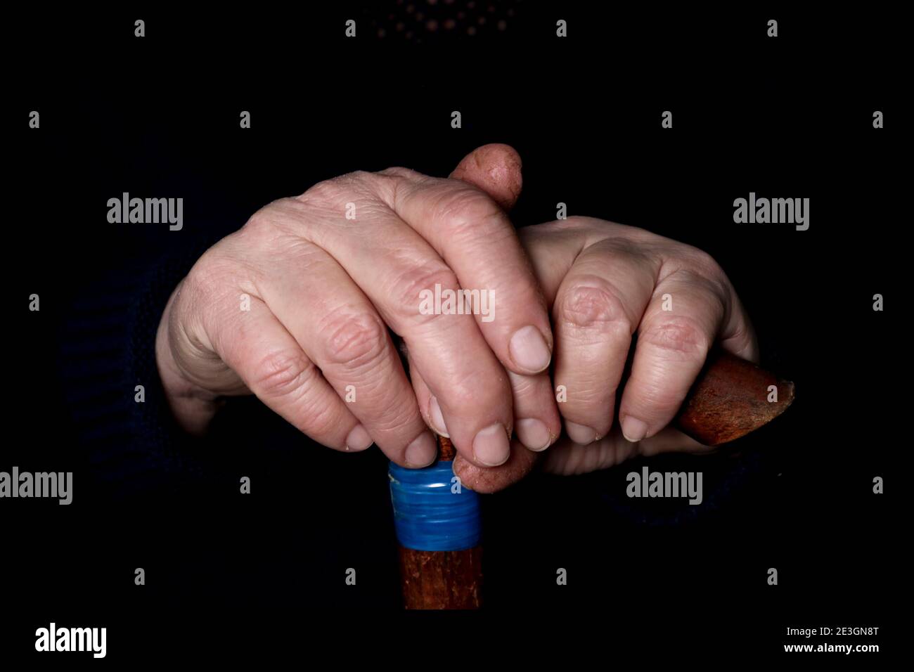 Elderly woman's hands on an old walking stick with t shaped handles. The concept of old age, loneliness, solicitude and caring for the elderly. Stock Photo