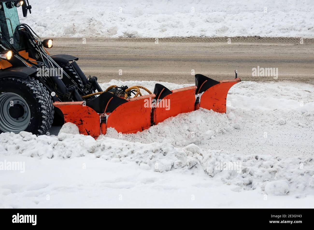 Removing snow with articulated snow plough from city street in winter. Stock Photo