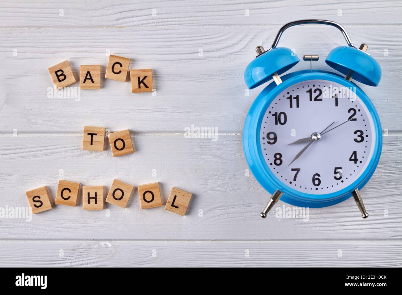 Blue alarm clock on white wood Stock Photo - Alamy