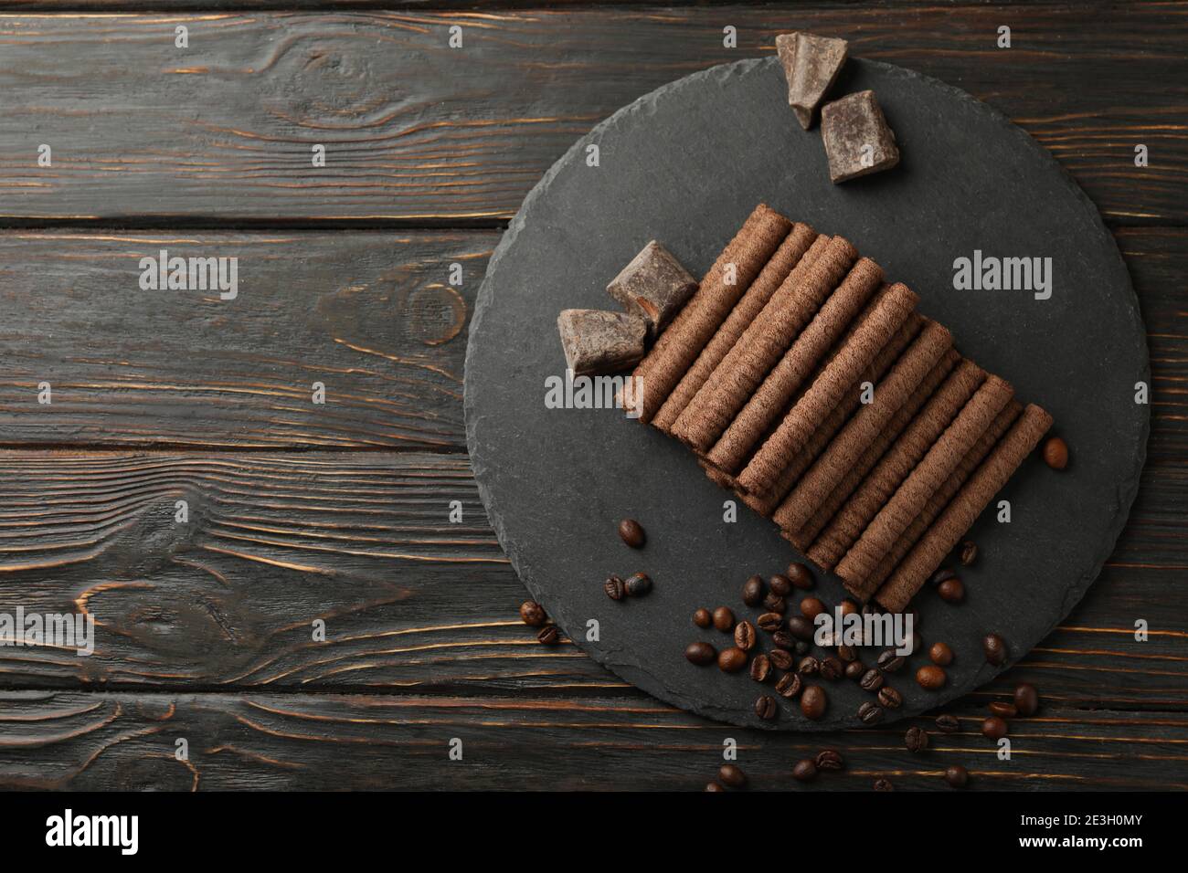 Tray with chocolate wafer rolls, coffee beans and chocolate on wooden background Stock Photo